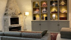 A living room with a stone fireplace, grey sofas, a floor lamp, and a decorative cabinet with shelves.