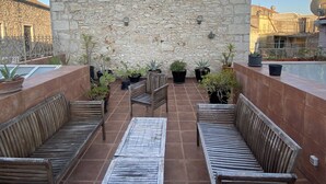 An outdoor patio with stone walls, wooden benches, and potted plants.
