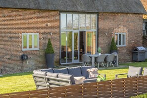 A brick house with a patio, a sofa, a table, and chairs.