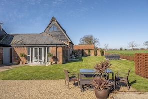 A house with a sloped roof, brick exterior, and a patio with outdoor furniture.