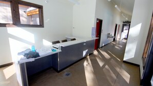 Un espace d’accueil comprenant un comptoir, une fenêtre et une porte donnant sur une autre pièce.