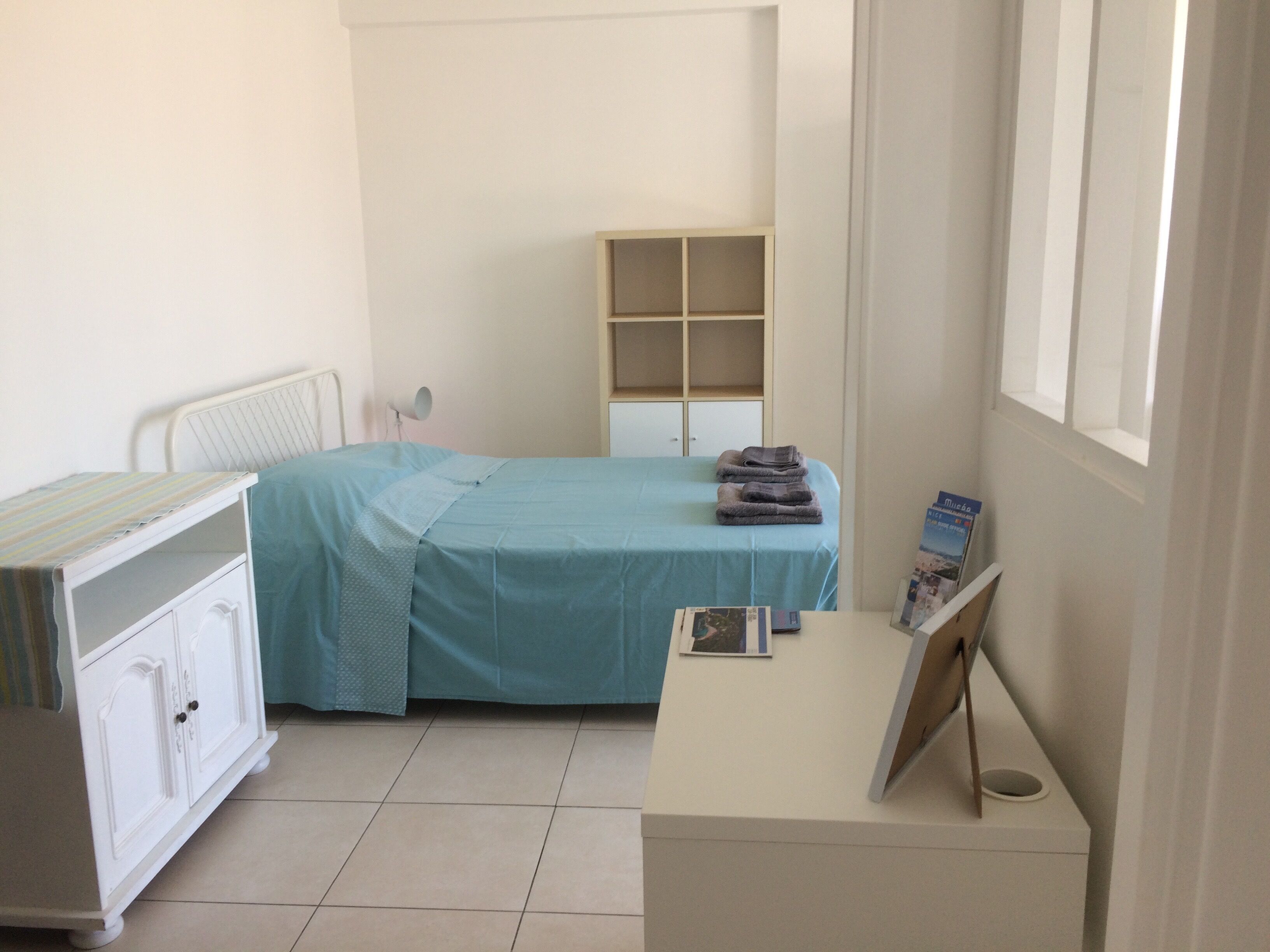 Ein Schlafzimmer mit Bett, Schminktisch, Ablagefläche und Fenster.