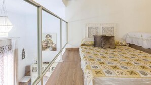 Una camera da letto con un letto grande, una testiera con pannelli decorativi, un comodino e vista attraverso una porta in vetro.