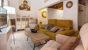 Un soggiorno moderno con un divano, poltrone, un tavolino da caffè e un televisore.