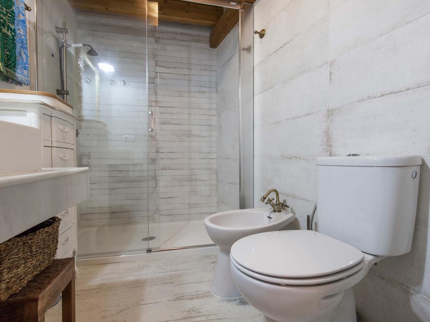 A bathroom with a shower, two toilets, and a sink.
