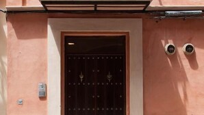 Un ingresso con una porta in legno scuro, un pannello di sicurezza in metallo e un sistema di ventilazione.