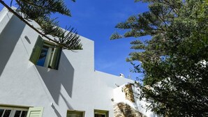 Ein modernes Gebäude mit weißer Fassade, grünen Fensterläden und einer Wand aus Naturstein.