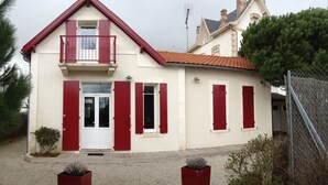 Une maison à deux étages avec un balcon, des volets rouges et un toit en tuiles.