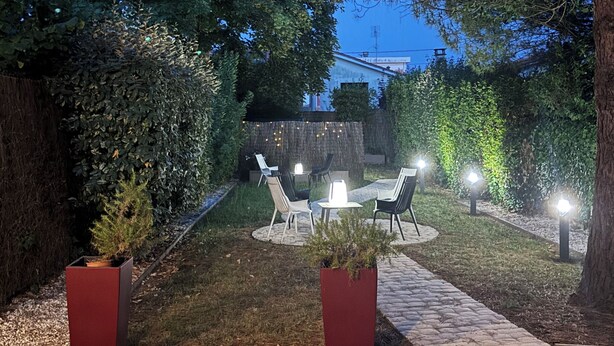 Un espace extérieur aménagé en terrasse, avec des sièges et des guirlandes lumineuses.