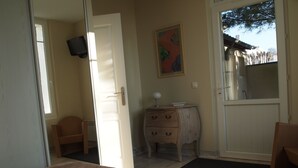 Une chambre à coucher comprenant un lit, une commode, une chaise et une porte donnant sur une autre pièce.
