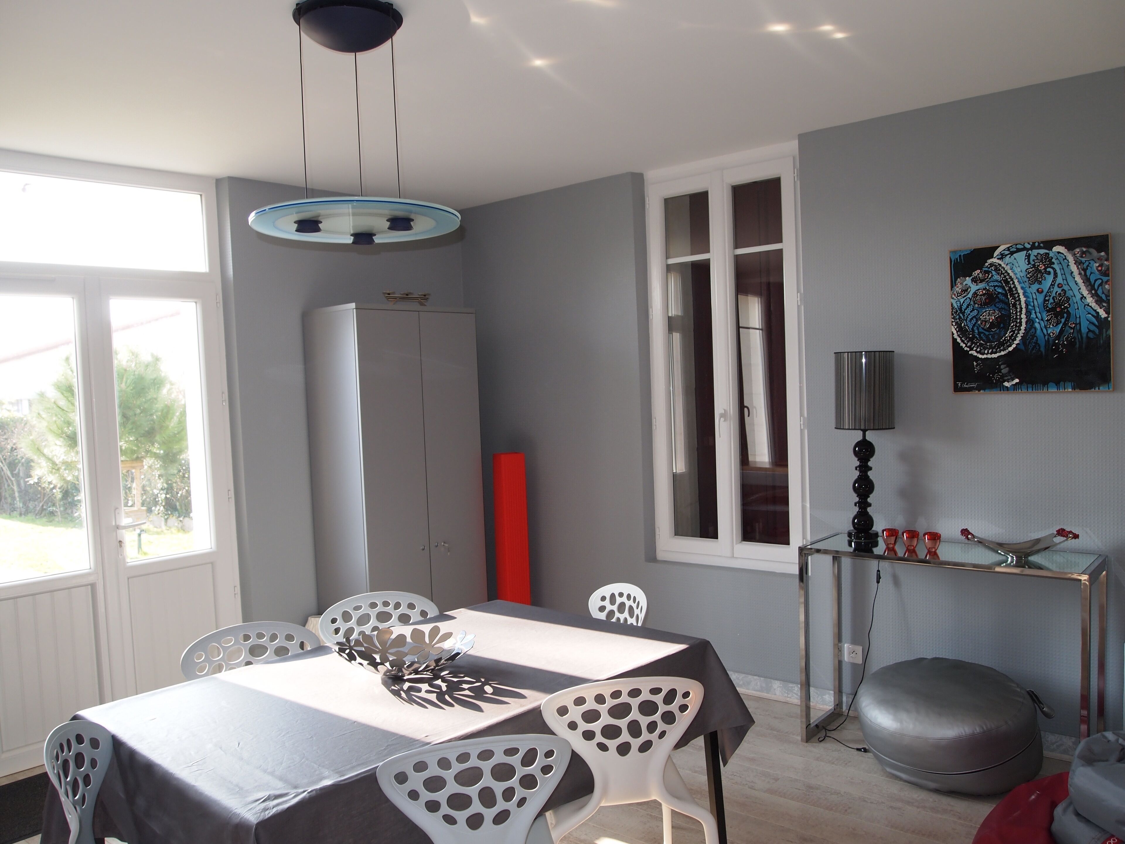 A dining area with a table, chairs, and a ceiling light fixture.