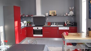 Une cuisine moderne avec des meubles rouges, un four blanc et un évier en acier inoxydable.