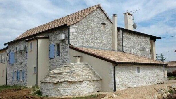 Um edifício de pedra com telhado inclinado, chaminé e antena parabólica.