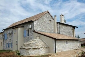 Un bâtiment en pierre avec un toit en pente, une cheminée et une antenne parabolique.