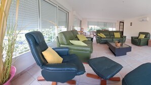 Uma sala de estar ampla com sofás de couro, uma mesa de centro e uma televisão.