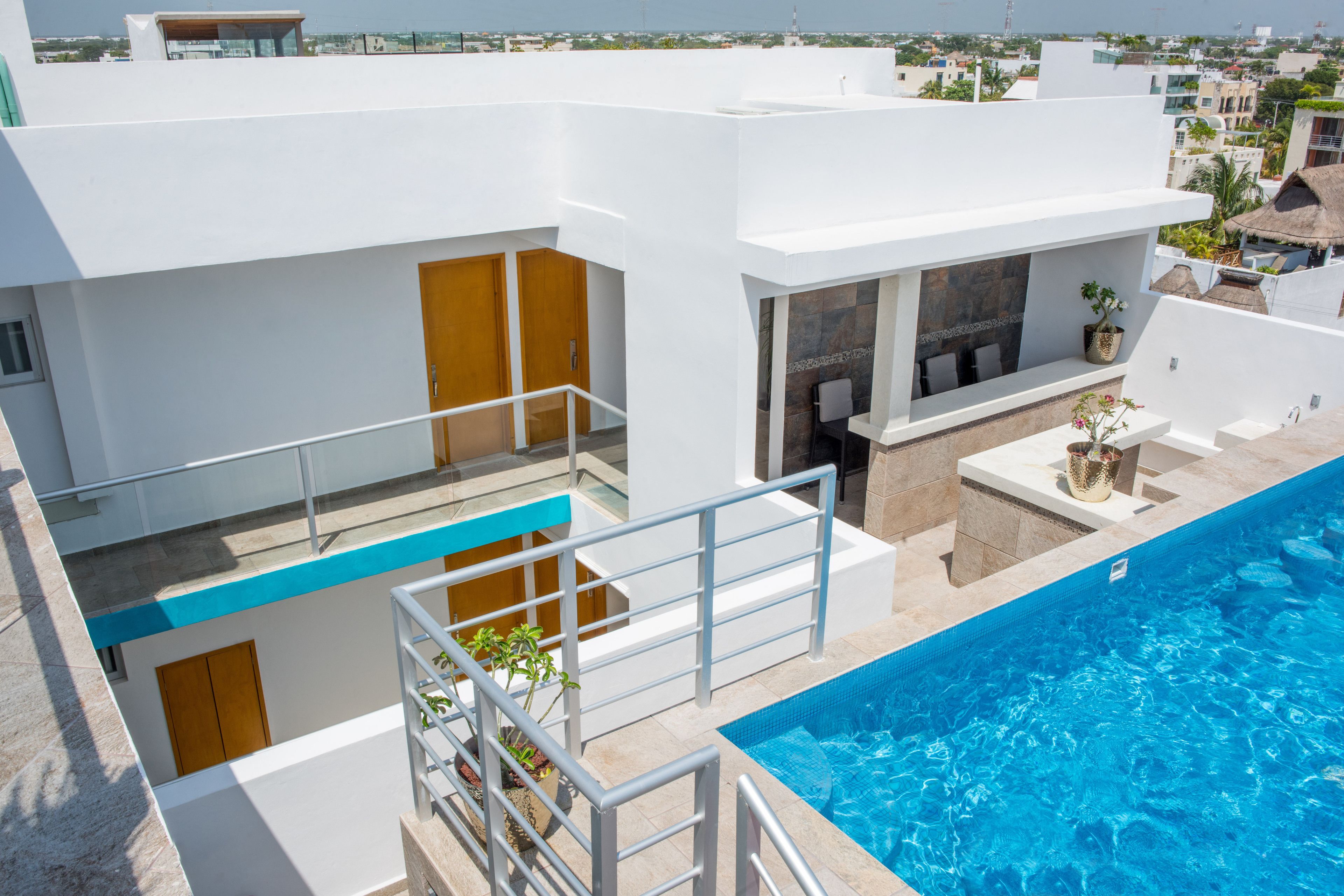 A modern building with a swimming pool, a balcony with a railing, and a small patio area with a table and chairs.