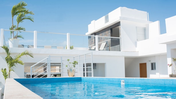 Un hotel moderno con piscina, un balcón con sillones de sol y vistas al cielo.
