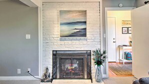 A living room with a fireplace, a peacock statue, and a painting above it. - Walk to Keller Beach: Waterfront Studio w/ Hot Tub (Point Richmond)