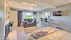 A modern hotel room with a sofa, a dining area, a flat-screen TV, and a large bed. - Walk to Keller Beach: Waterfront Studio w/ Hot Tub (Point Richmond)