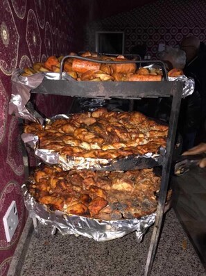 A metal rack with multiple trays of cooked food, likely for a gathering or event. - Jamal rum camp (Wadi Rum)
