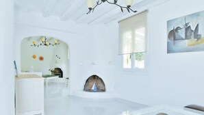 A bright, white interior with a fireplace, a dining area, and a modern art piece on the wall. - Cozy 2-bedroom House in Tinos (Tinos)