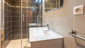 A modern bathroom with a glass-enclosed shower, a white sink, and a mirror. - 2** Apartment for 6, South, near slopes and shops (La Clusaz)