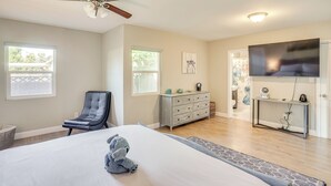 A bedroom with a bed, a ceiling fan, a dresser, a TV, and a window.