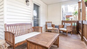 A covered porch with a wooden bench, two chairs, and a table. - Laurel Reef | Pet Friendly, Charming Home! (Tybee Island)