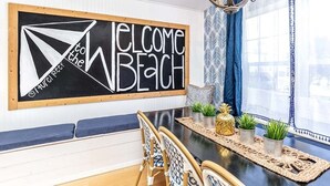 A dining area with a blackboard sign reading "WELCOME to the BEACH" and a modern chandelier. - Laurel Reef | Pet Friendly, Charming Home! (Tybee Island)