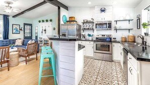 A modern kitchen with white cabinets, stainless steel appliances, and a patterned floor. - Laurel Reef | Pet Friendly, Charming Home! (Tybee Island)