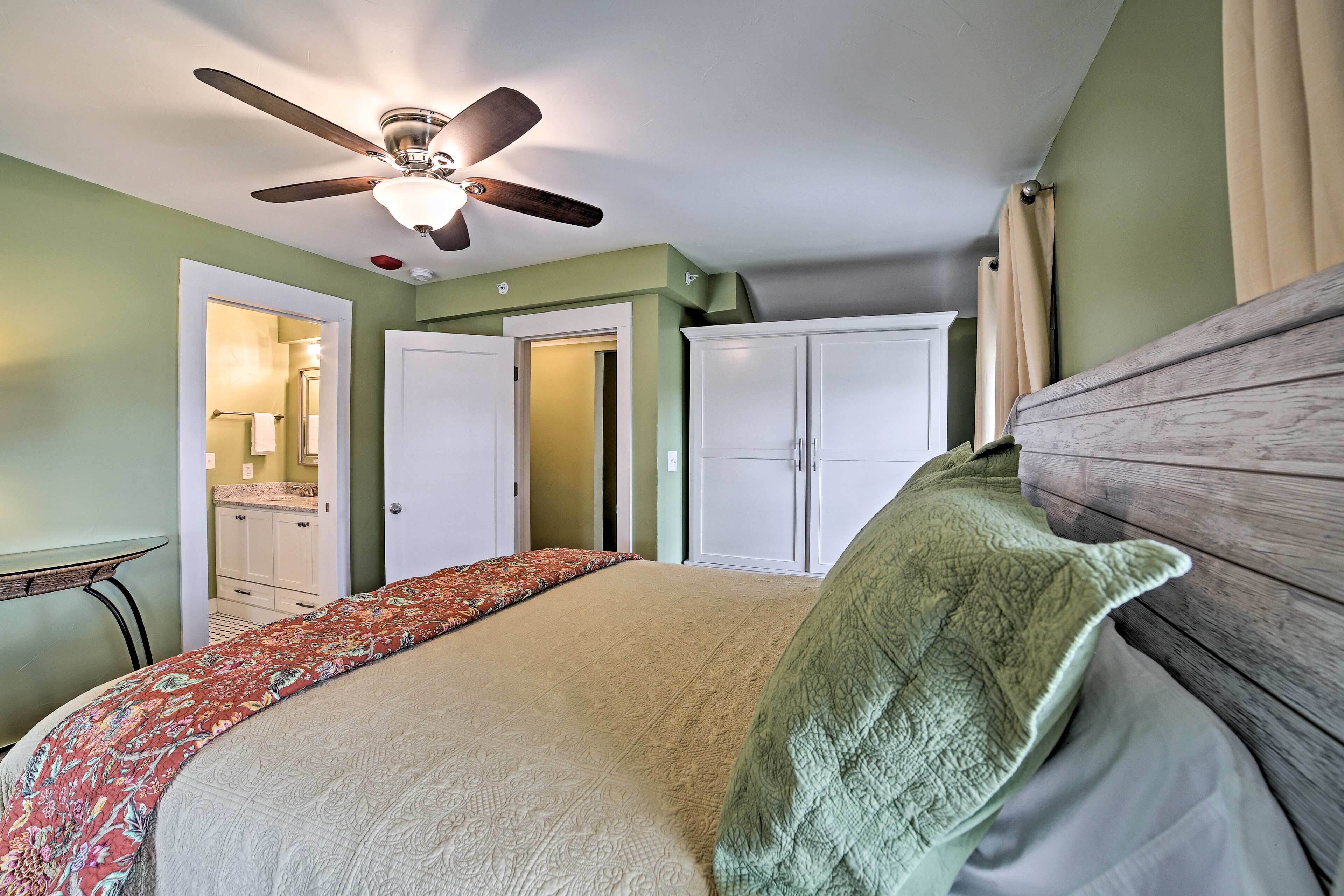 A bedroom with a bed, a ceiling fan, a wardrobe, and a small table.