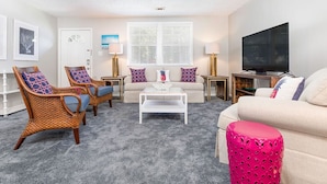 A living room with a sofa, two armchairs, a coffee table, a TV, and a lamp. - Latitude Adjustment | Pet Friendly, Prime Location (Tybee Island)
