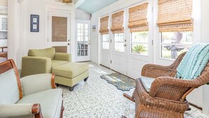 A spacious room with a patterned floor, wicker furniture, and a decorative ceiling light. - Sunny Daze | Large Patio + Fire Pit! (Tybee Island)