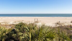 Ein Strand mit sandigem Ufer, spärlicher Vegetation und blauem Himmel.