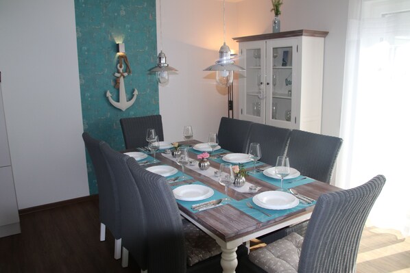 A dining table set for six with chairs, a cabinet with glass doors, and decorative wall anchors.