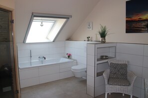 Een bad/douchecombinatie, een haardroger, zeep, toiletpapier