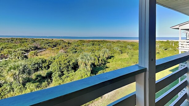 Un balcon donnant sur une plage et une végétation luxuriante.