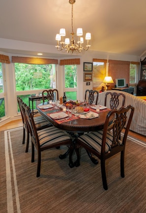 A dining room with a round table, wooden chairs, and a chandelier.