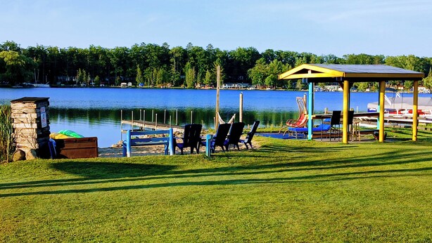 A lakeside gazebo with chairs and a dock extending into the water. - Lakefront/Wifi /Coffee/ Stocked Cabin /Kayaks /Beach/Firepit hammocks /Pet (Harrison)