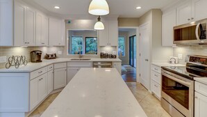 A modern kitchen with white cabinetry, a large island, stainless steel appliances, and a view to the outdoors. - 4 Hollyberry - Dog Friendly.  Great Community Amenities (Hilton Head Island)