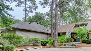 A two-story house with a front porch, a small garden, and a flag. - 4 Hollyberry - Dog Friendly.  Great Community Amenities (Hilton Head Island)