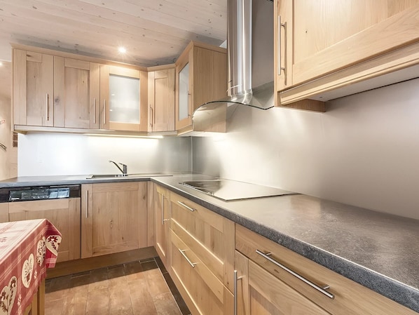 A modern kitchen with wooden cabinets, a stainless steel range hood, and a granite countertop.