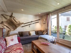 Ein Zimmer mit einem aufgehängten Tierkopf, einer Couch, einem Tisch und einem Fenster mit Blick auf Gebäude und Bäume.