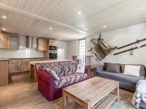 Una sala de estar con un sofá, una mesa de centro y una zona de comedor con una mesa y sillas.