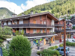 A multi-story hotel with balconies, a ski location sign, and a view of a mountainous area. - Cozy apartment near shops, central location, garage included, pets allowed (La Clusaz)