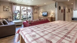 A cozy room with a large bed, a sofa, a TV, and a dining table.