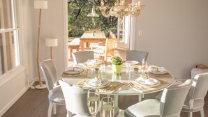 A dining area with a glass table, white chairs, and a chandelier. - Spa-like Estate, Wine Country Getaway, above the Sonoma Square, Amazing Views (Sonoma)