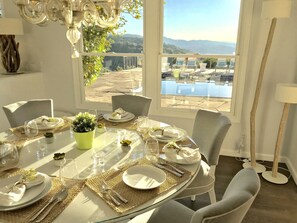 A dining area with a table set for four, overlooking a pool and mountains.