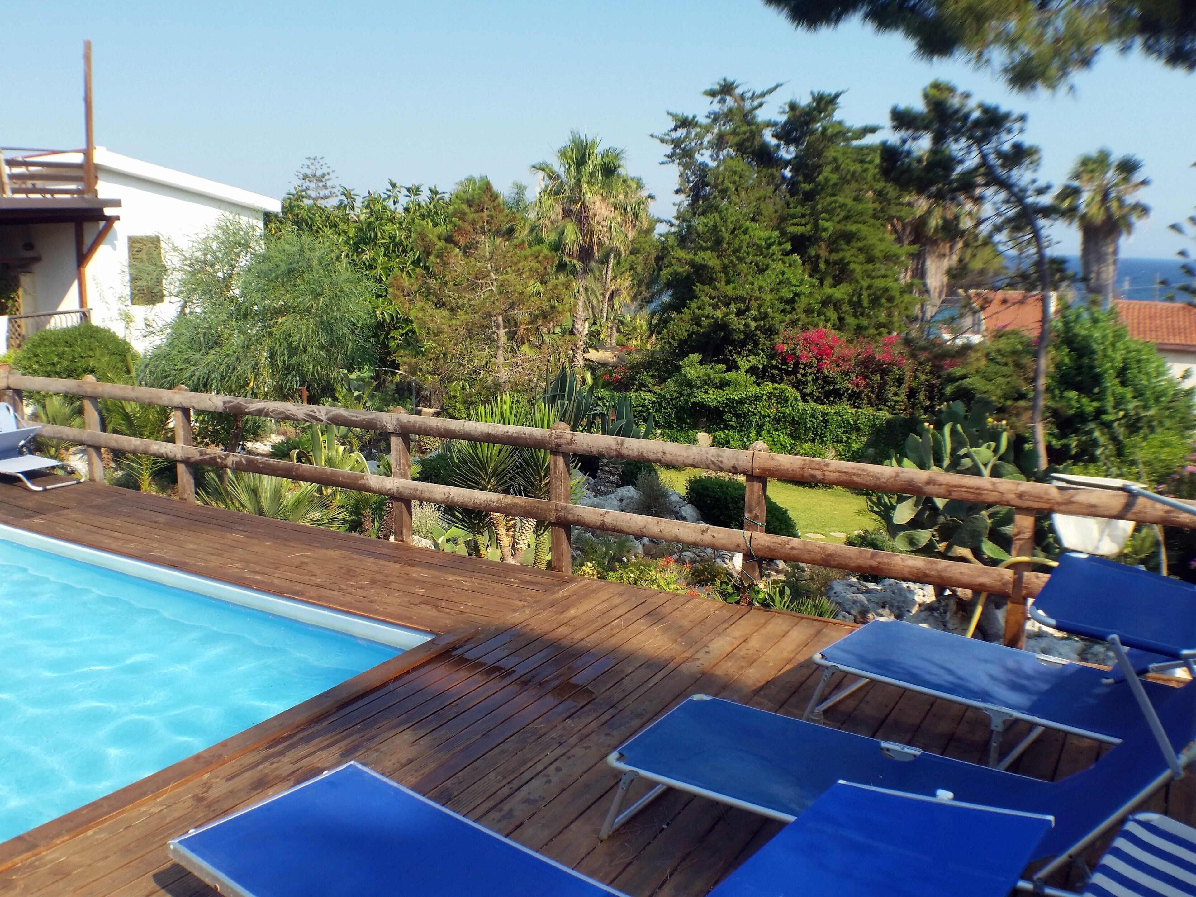 A wooden deck with a pool and lounge chairs.