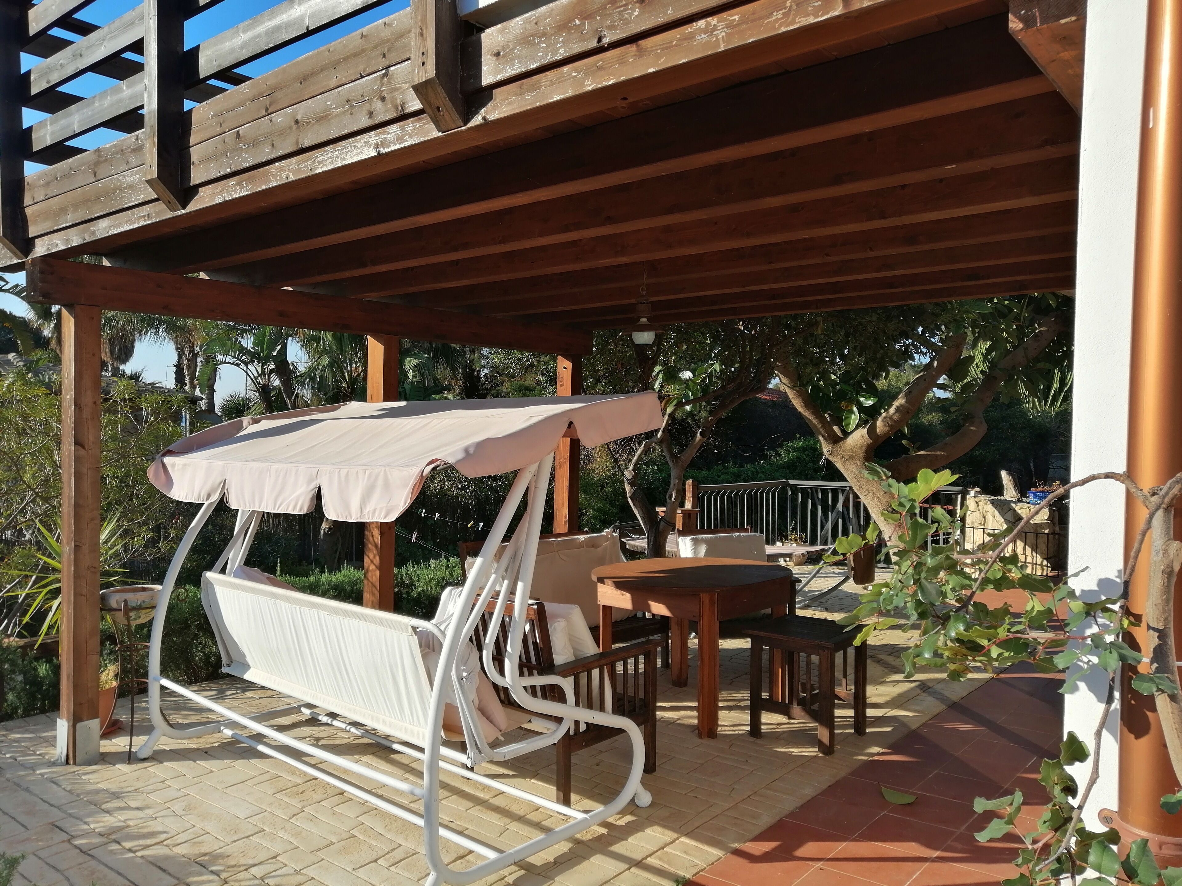 Un espacio de estar al aire libre con techo, una silla colgante y una mesa.